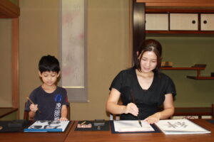 A photo of the participants enjoying the calligraphy session. One of them is a mother and the other is her son.