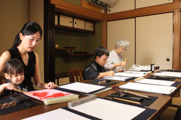 A photo of four participants practicing calligraphy.