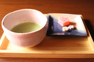 A photo of  a cup of matcha and some Japanese sweets.