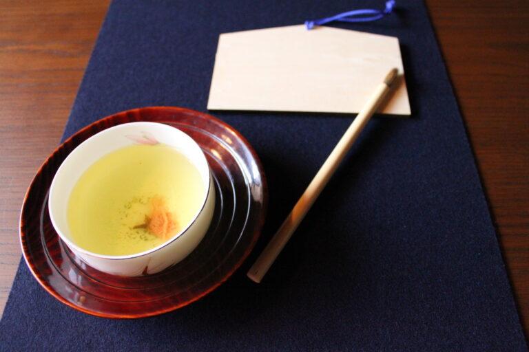 A photo of the set for the special new year calligraphy experience, with a cup of tea, an ema board, and a brush.