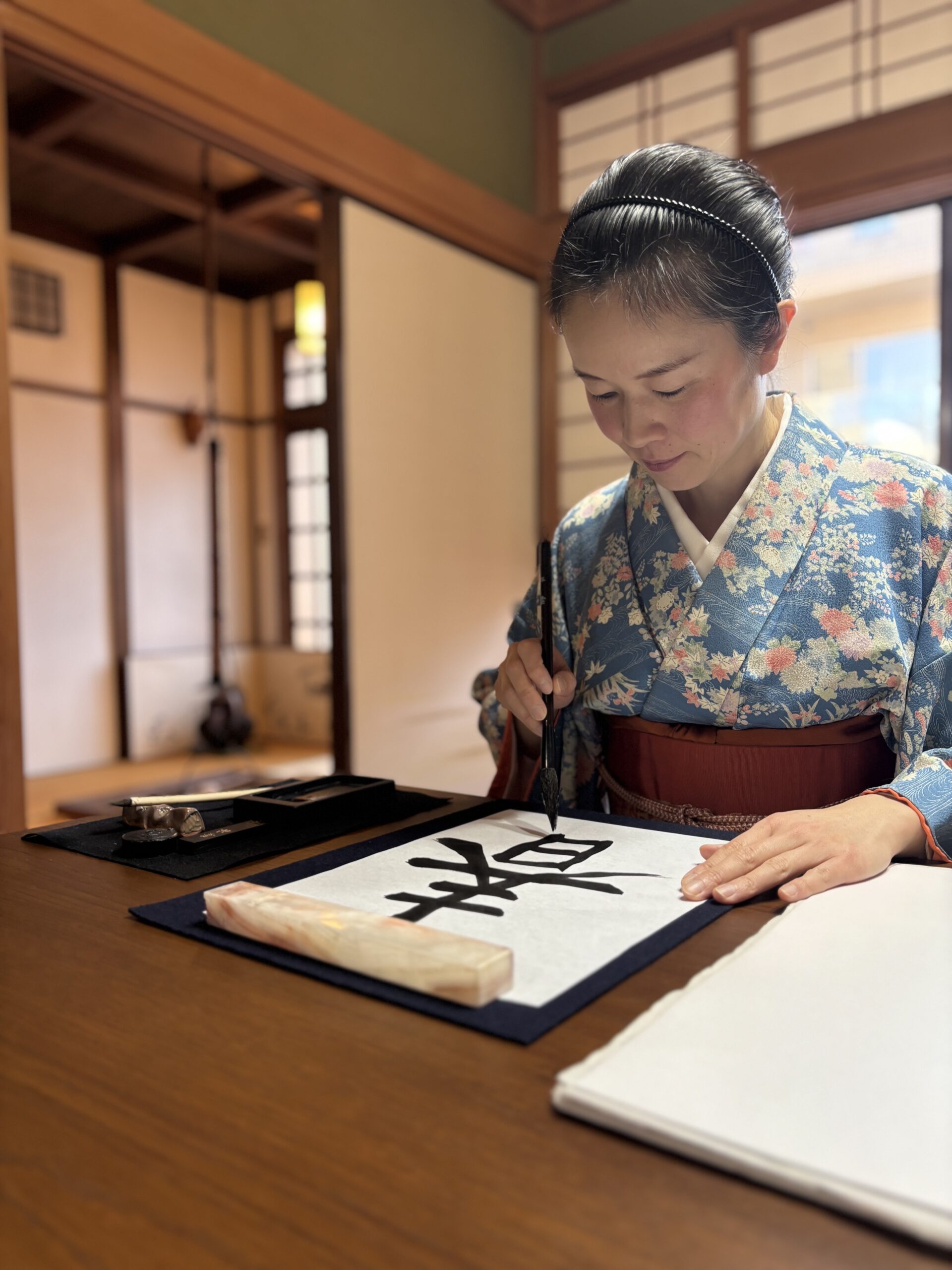 A photo of the shop owner writing 春 spring in calligraphy.