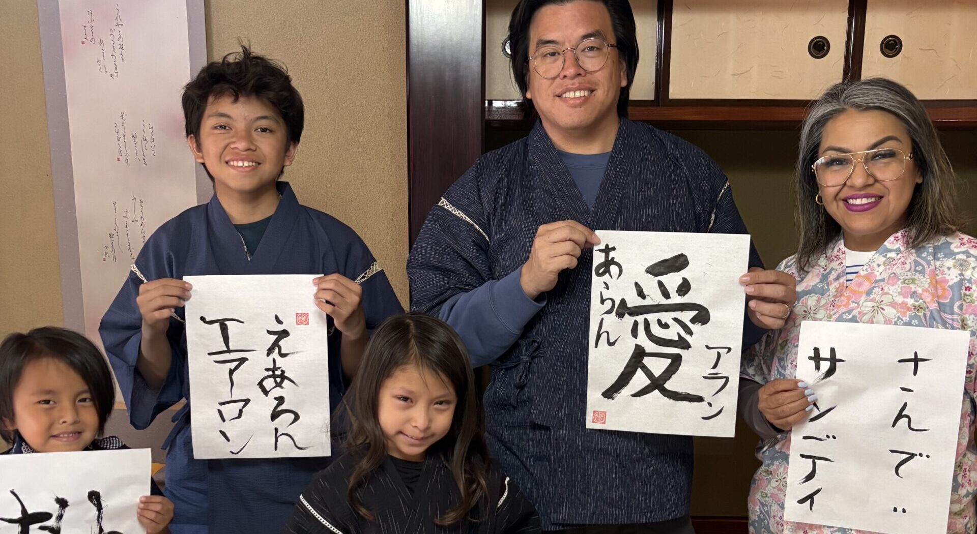 A photo of each family member holding their own calligraphy piece.