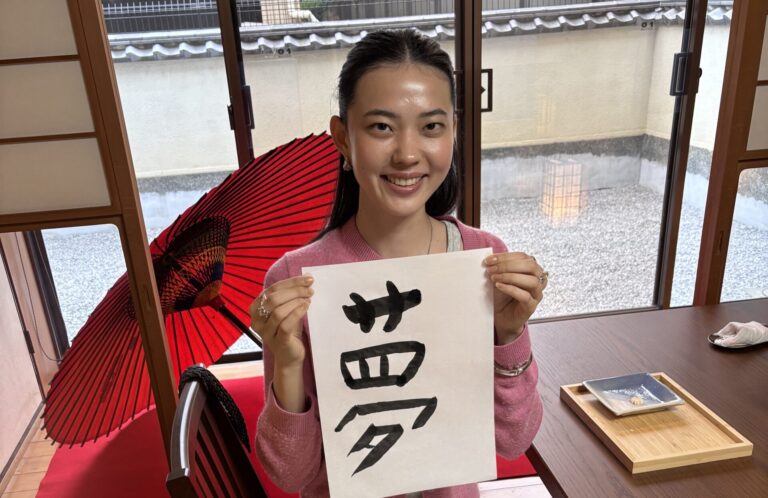 A photo of the guest holding her calligraphy piece, "Dream."