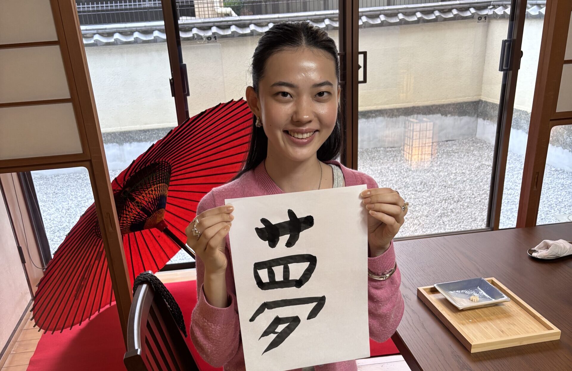 A photo of the guest holding her calligraphy piece, "Dream."