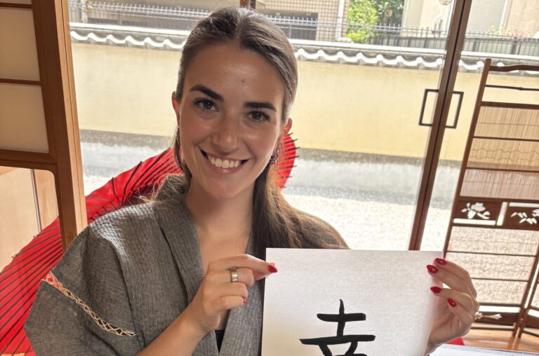 A photo of our guest holding her calligraphy work "happiness".