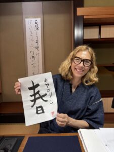 A photo of our guest holding her calligraphy work "spring".