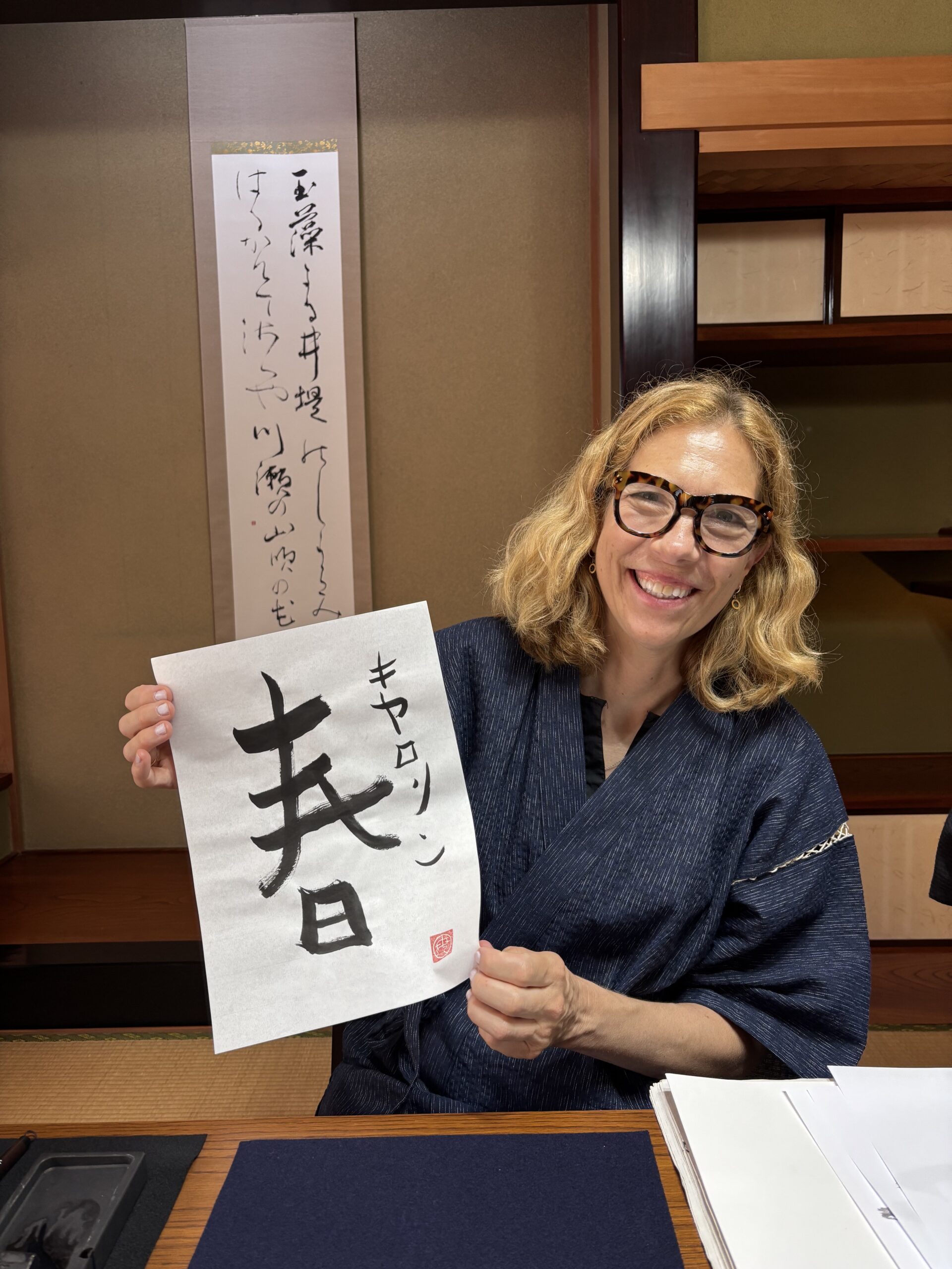 A photo of our guest holding her calligraphy work "spring".