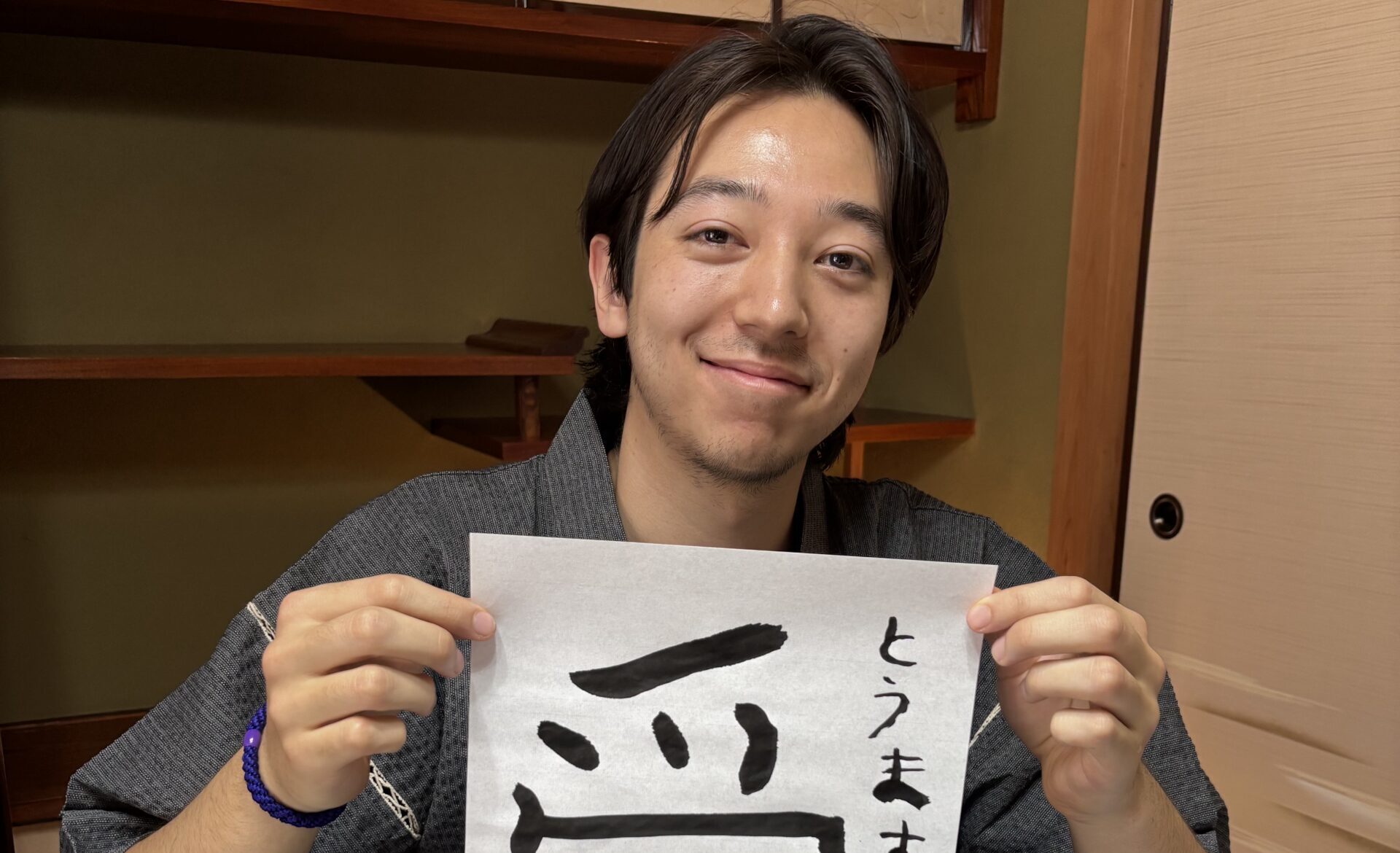 A photo of our guest holding his calligraphy work "love".