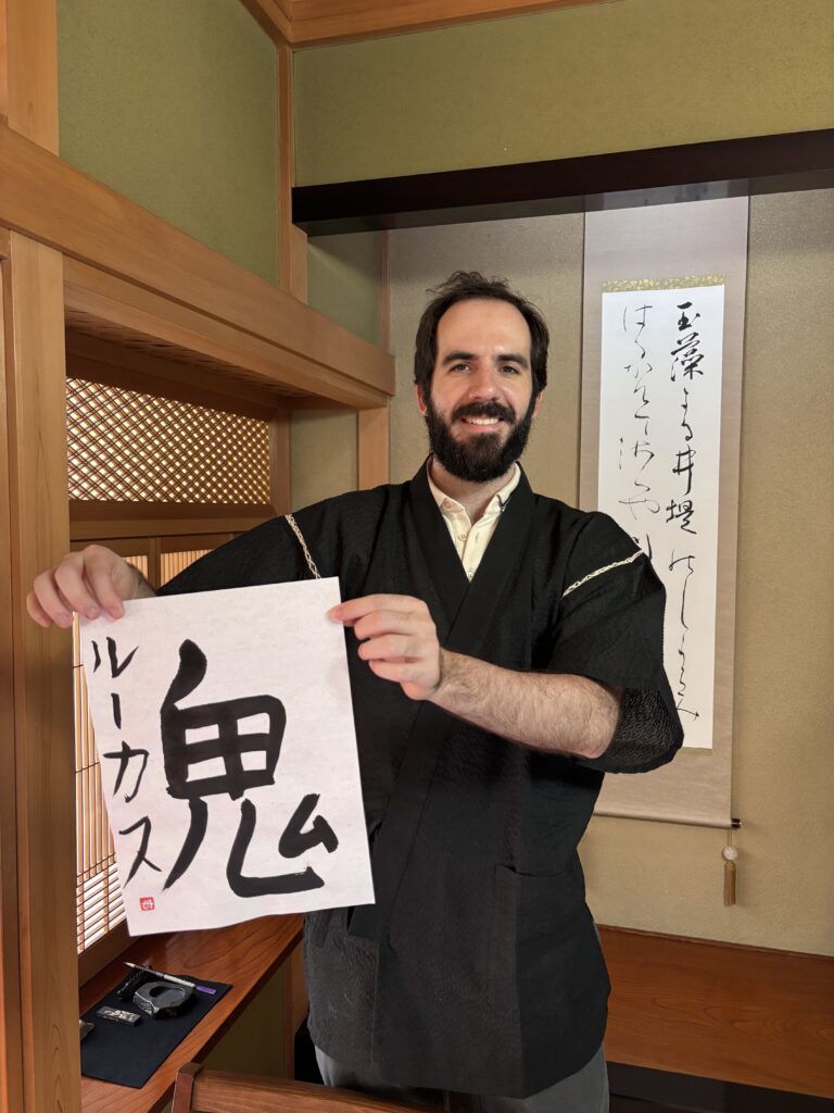 A photo of our guest holding his calligraphy work "oni".