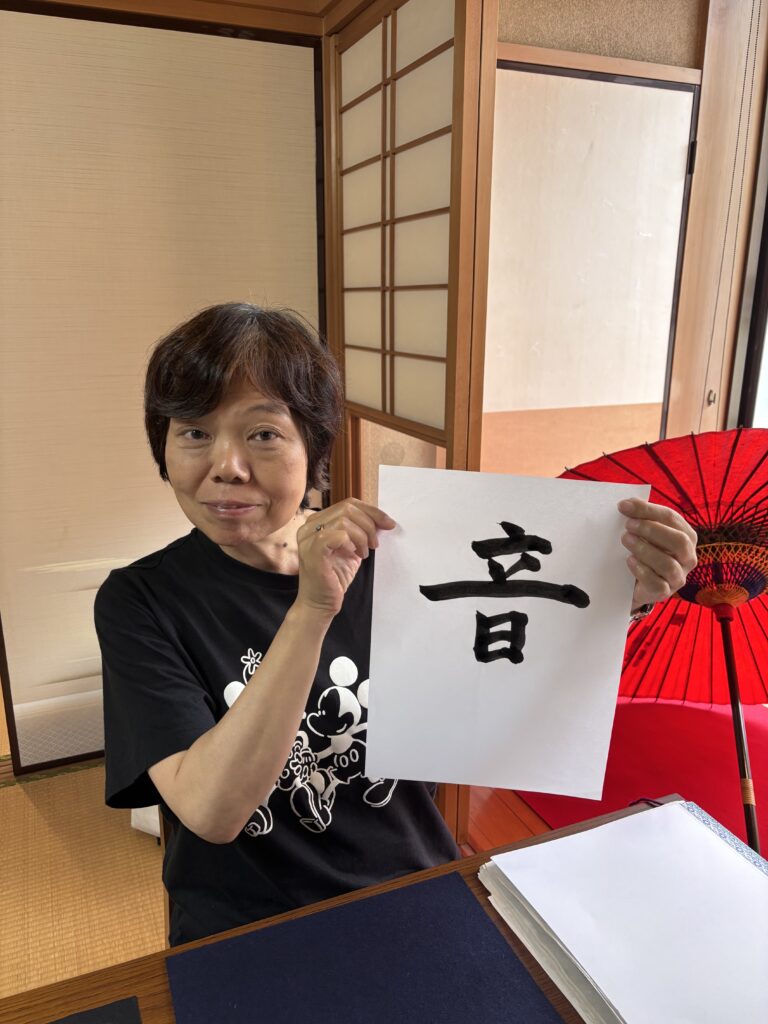 A photo of our guest with her calligraphy work.
