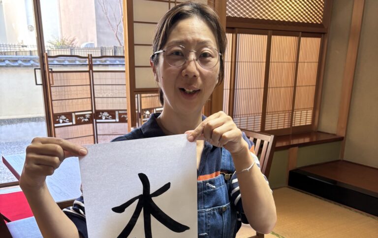A phot of our guest holding her calligraphy work.