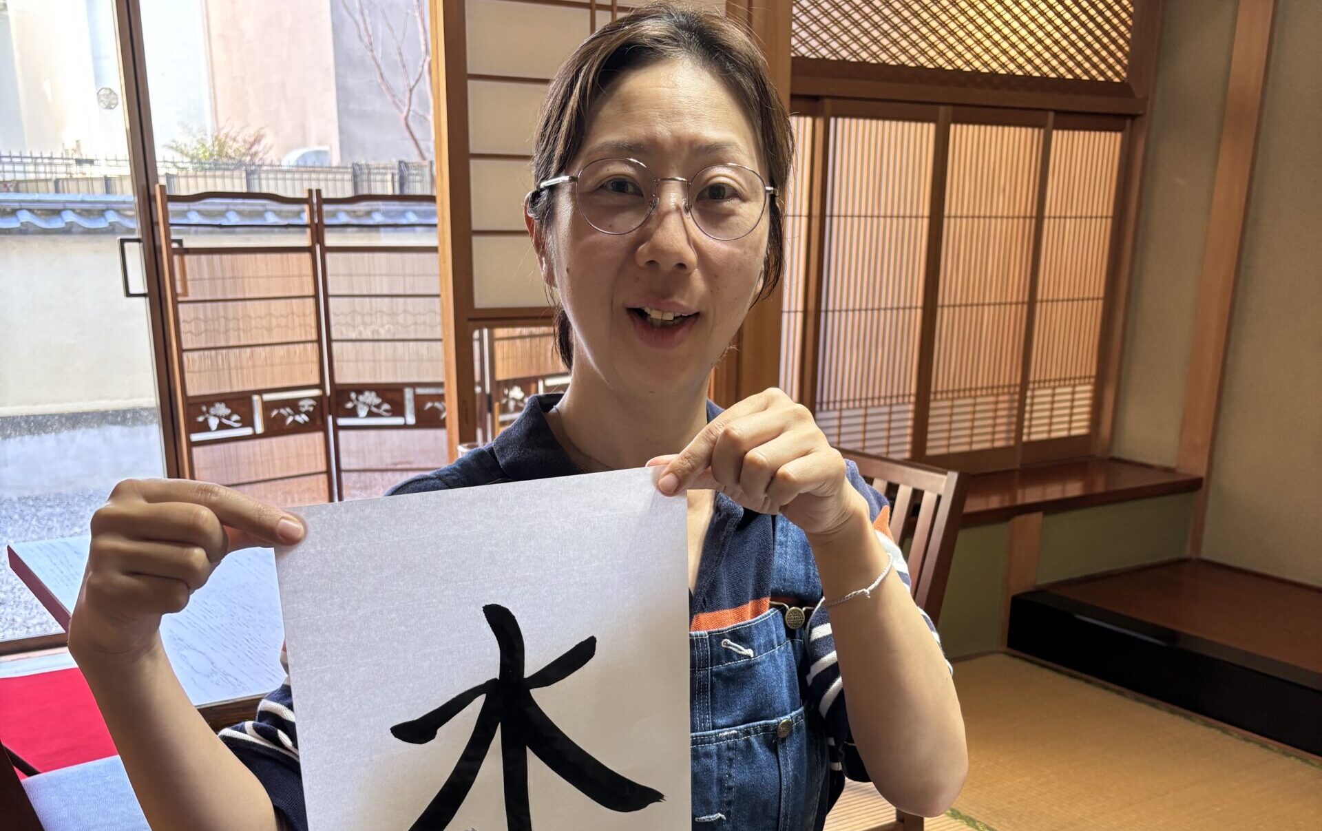 A phot of our guest holding her calligraphy work.