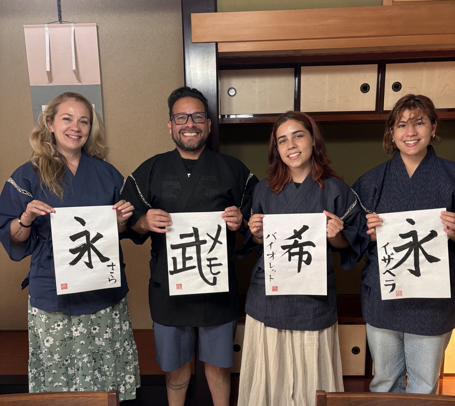A group photo of our guests holding their best pieces of calligraphy.