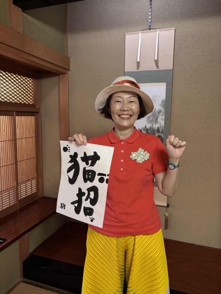 A photo of our guest with her calligraphy piece “猫招” (meaning “cat invitation”) .