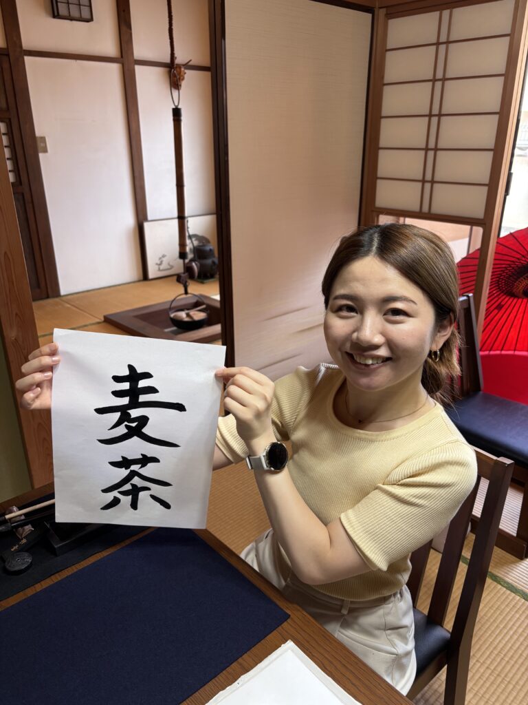 A photo of our guest and her calligraphy piece "Mugicha" (barley tea).