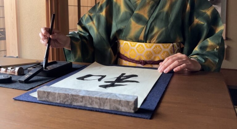 A photo of the manager writing "wa" in calligraphy.