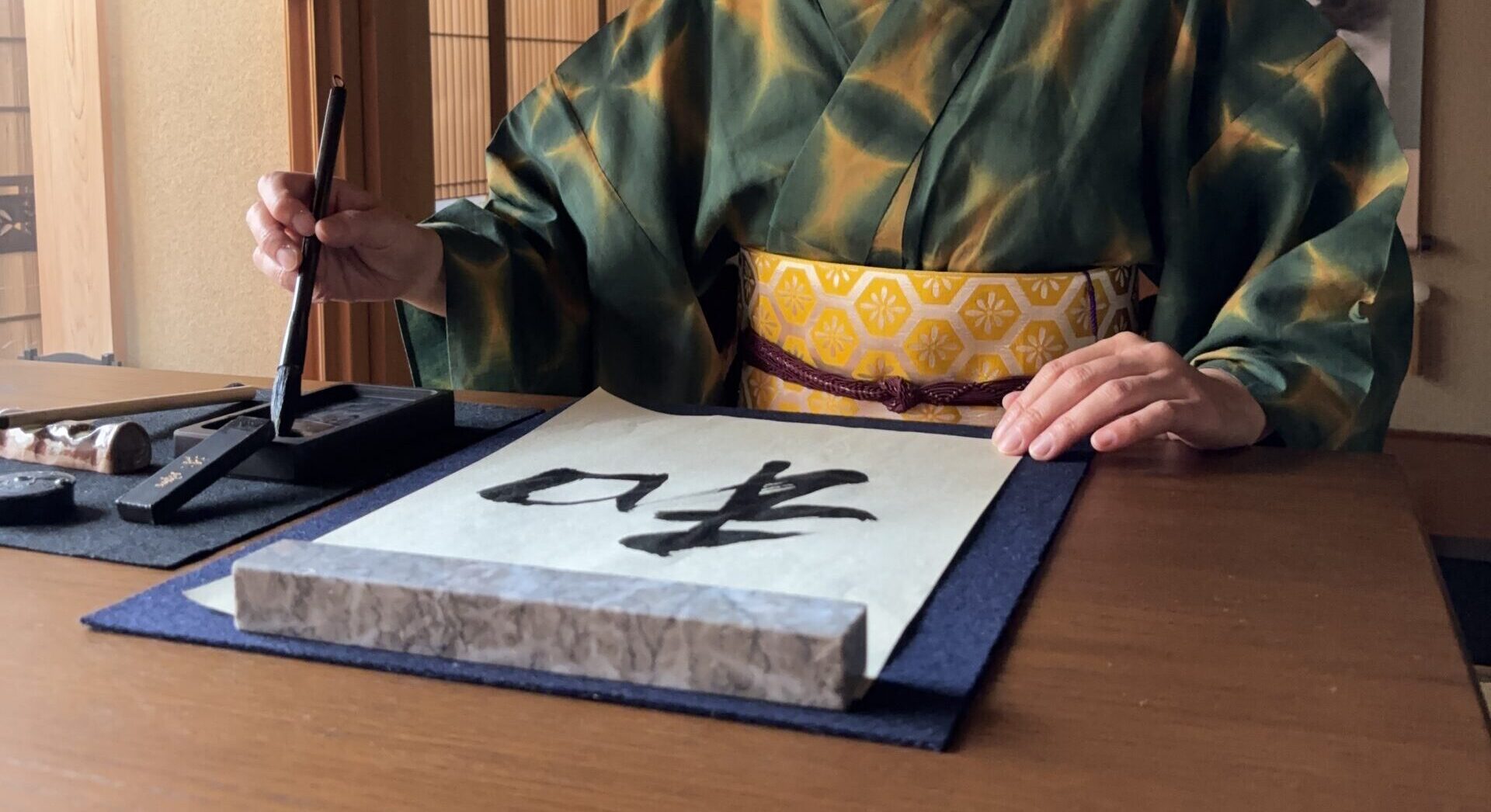 A photo of the manager writing "wa" in calligraphy.
