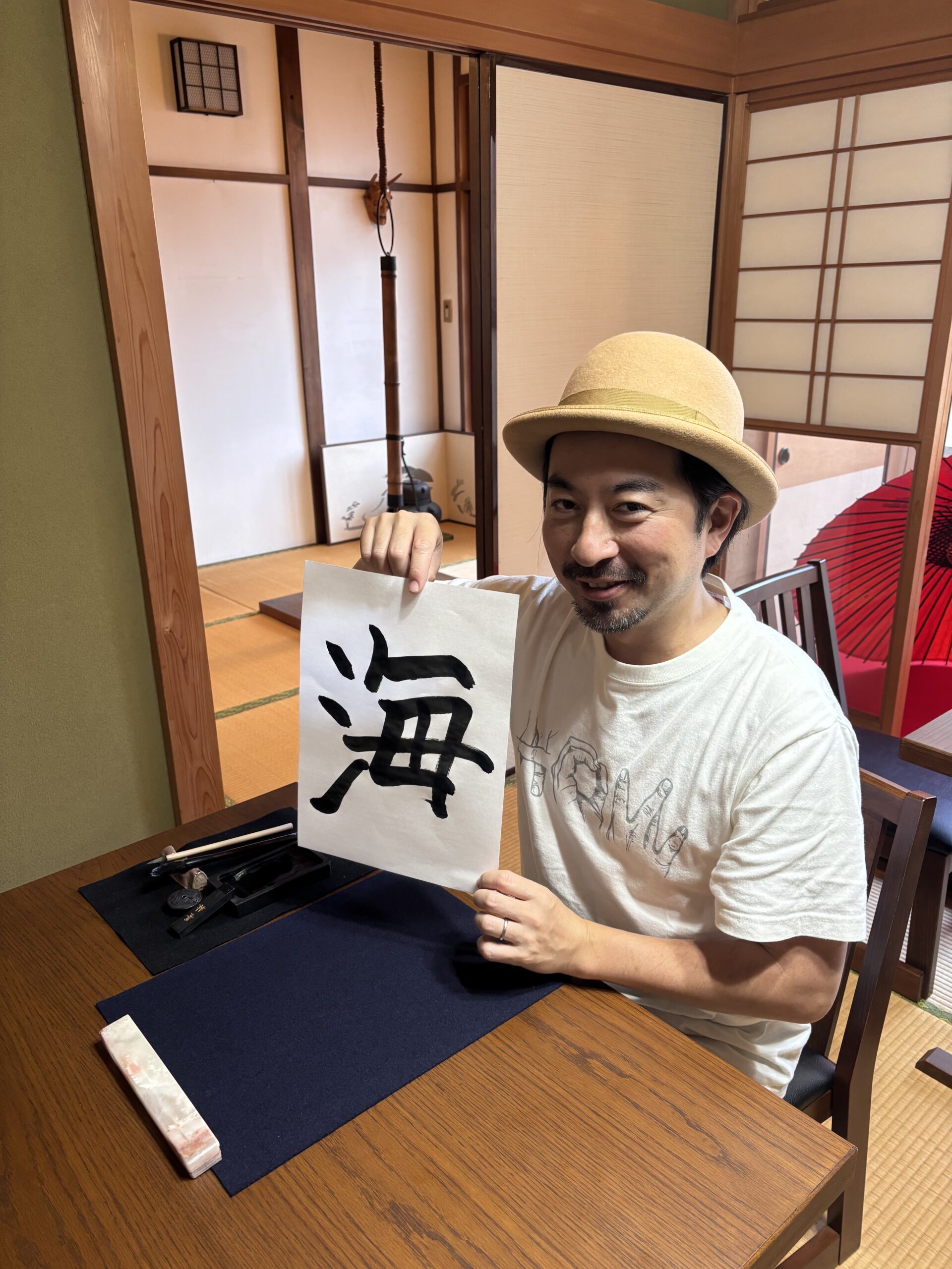 A photo of our guest with his calligraphy work written "umi".