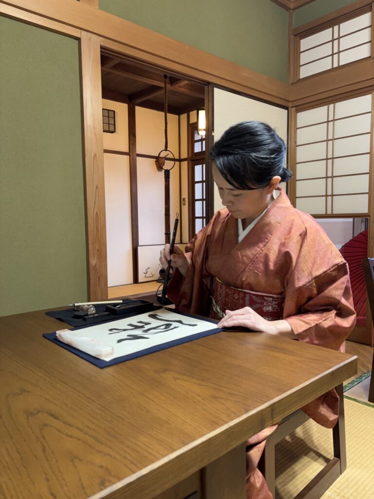 The manager writing the word 熊 in calligraphy at our salon.