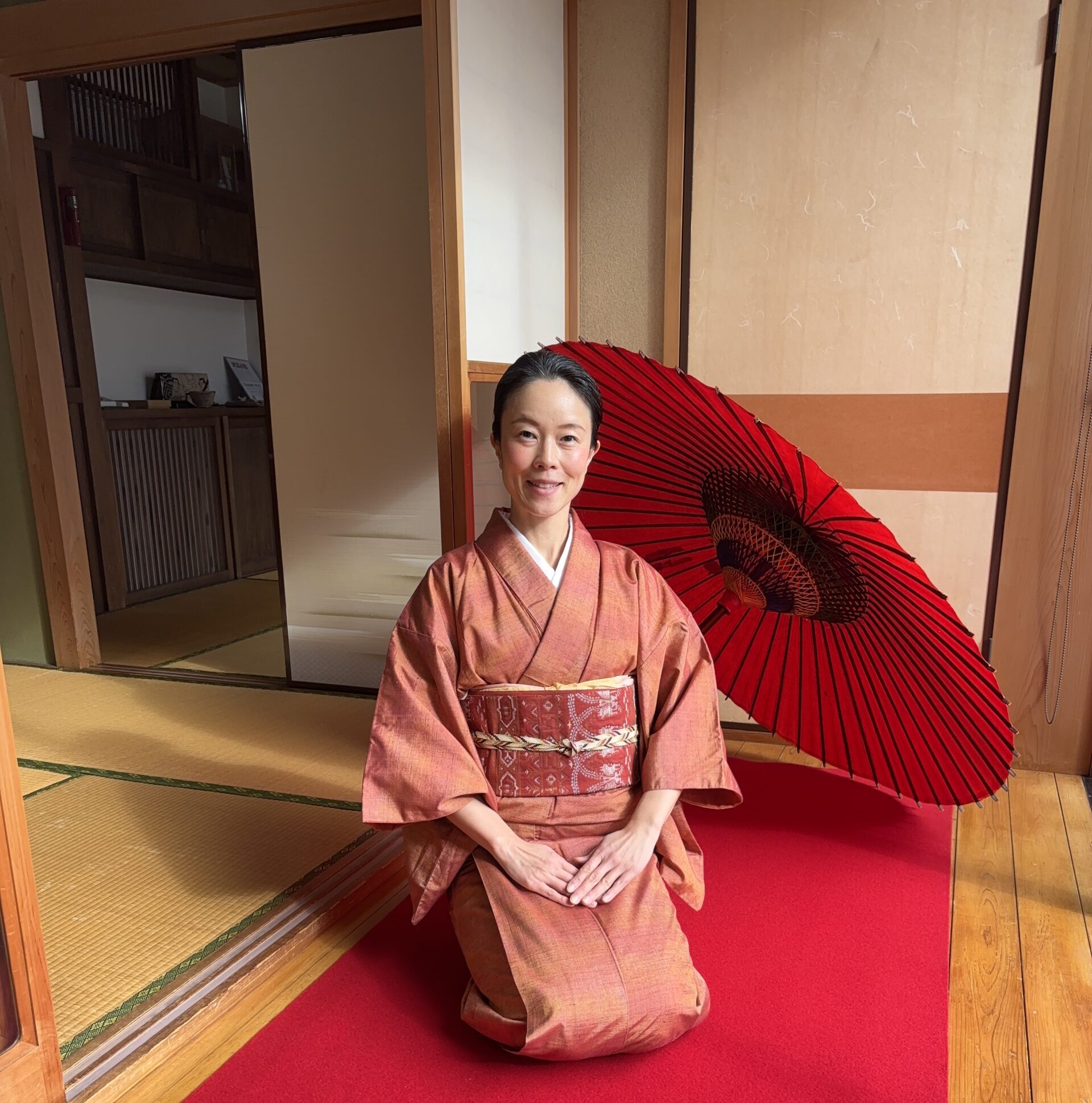 The manager is sitting in front of a red Japanese umbrella.