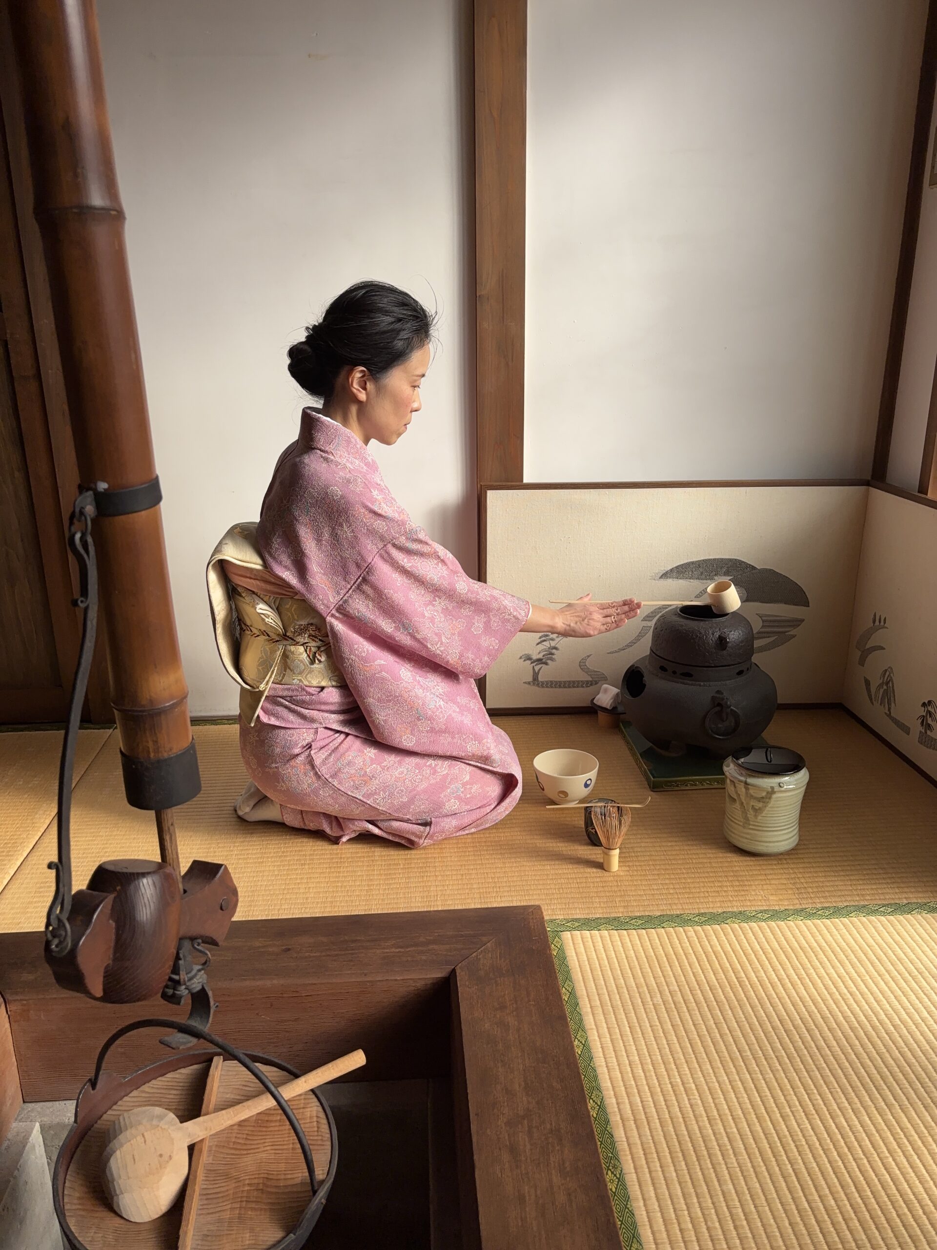 The manager in kimono handling a tea utensil in the tea ceremony.