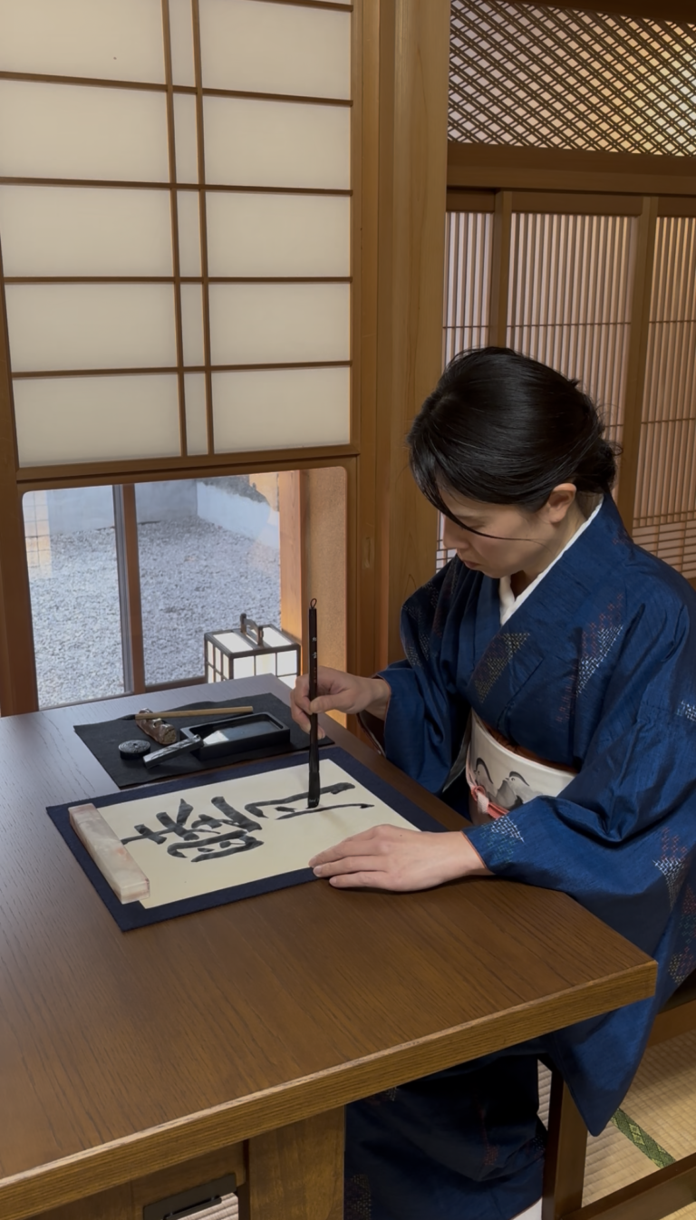 The manager writing the word 睦月 in calligraphy at our salon.