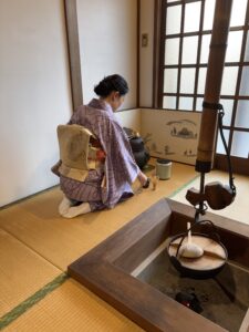 The manager in kimono handling a tea utensil in the tea ceremony.