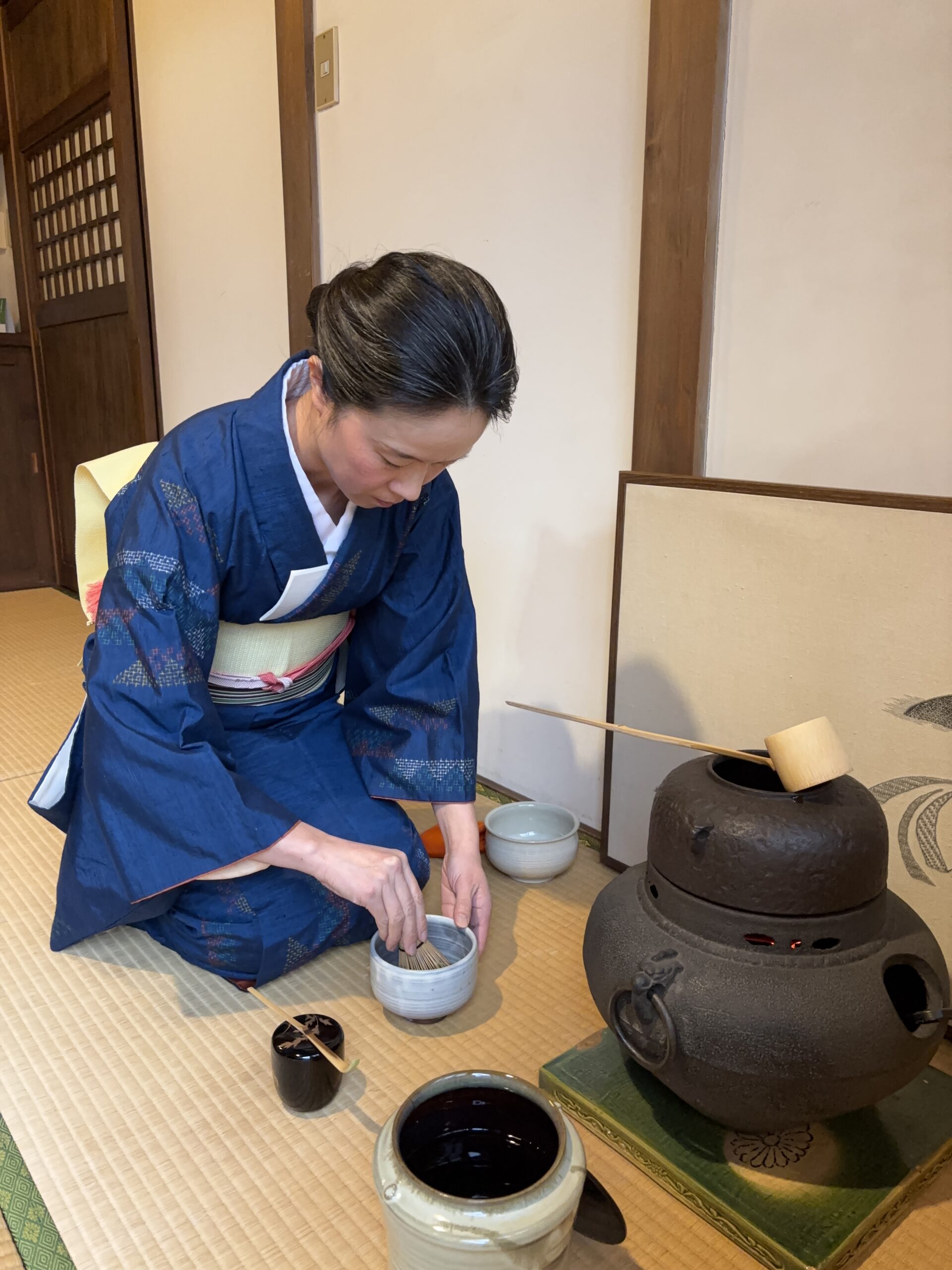 The manager in kimono handling a tea utensil in the tea ceremony.