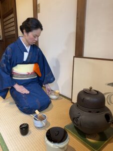 The manager in kimono handling a tea utensil in the tea ceremony.