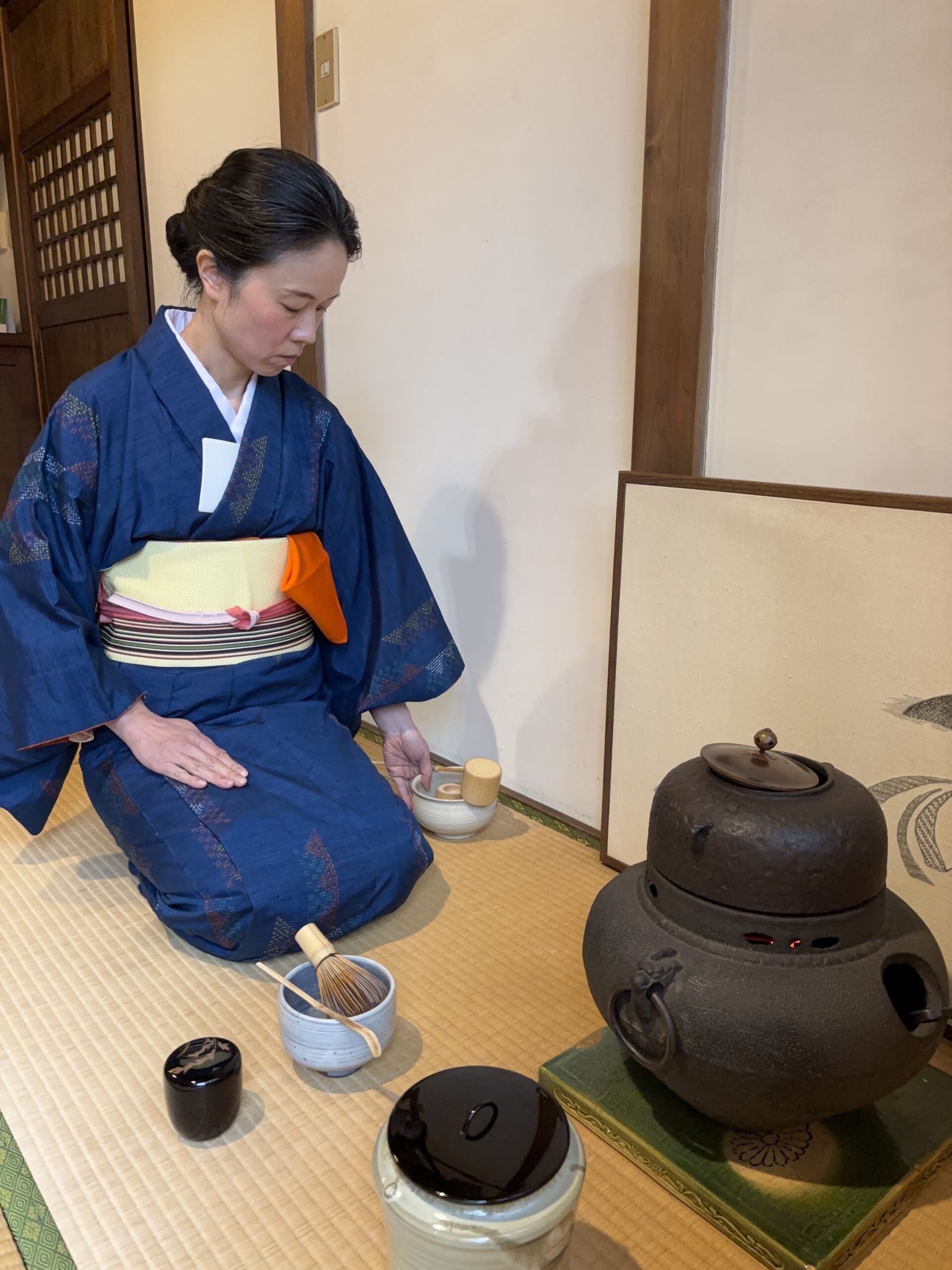 The manager in kimono handling a tea utensil in the tea ceremony.