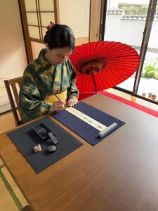 The manager writing on a tanzaku with a brush and ink.