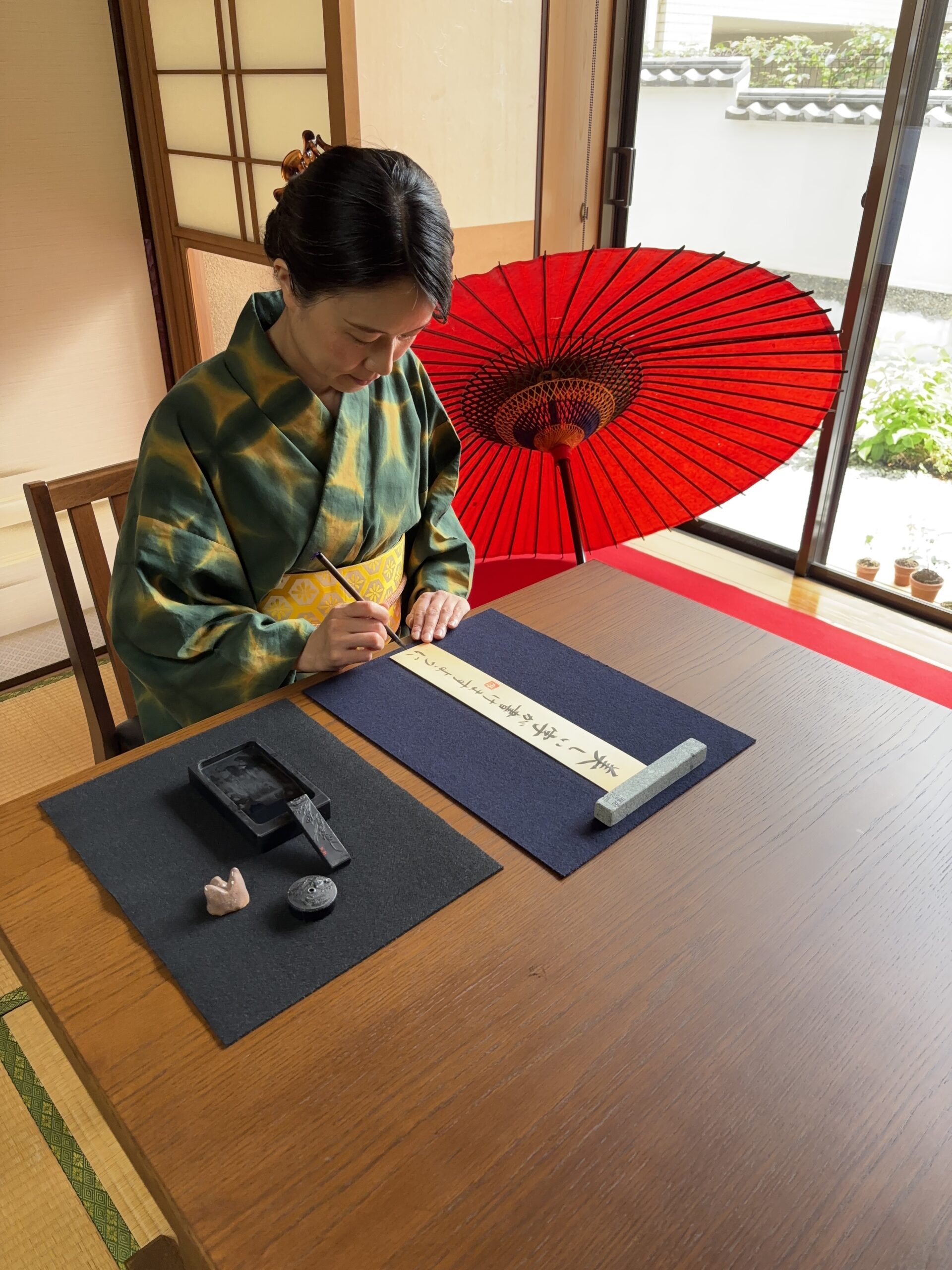 The manager writing on a tanzaku with a brush and ink.